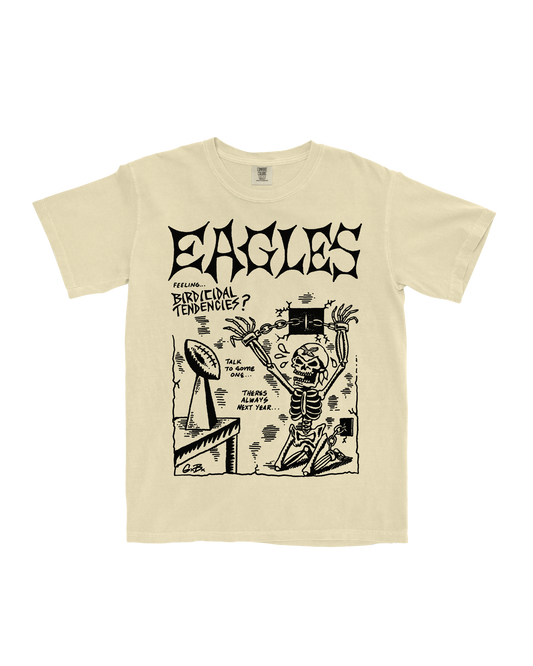 Beige t-shirt with black graphic design featuring a skeleton and text on a white background