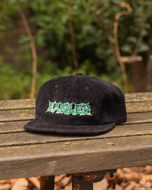 Black cap with 'EAGLES' logo on a wooden surface with a blurred natural background