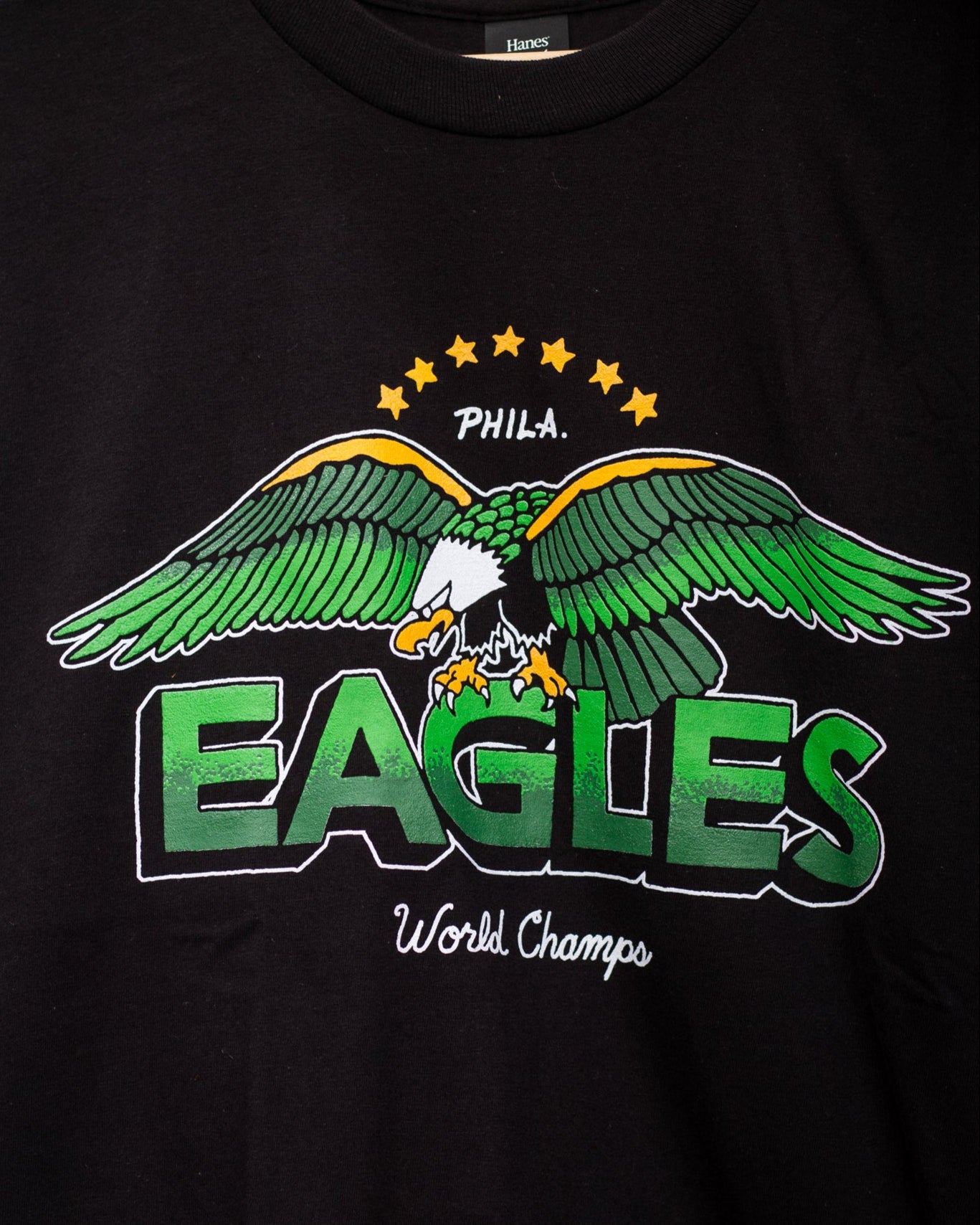 Black t-shirt with Eagles logo and text on a chain-link fence background
