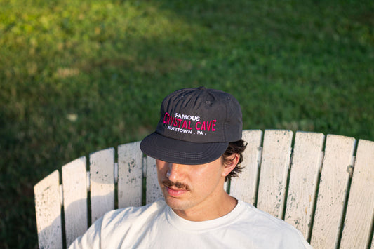 Person wearing a cap with text sitting on a wooden chair outdoors.