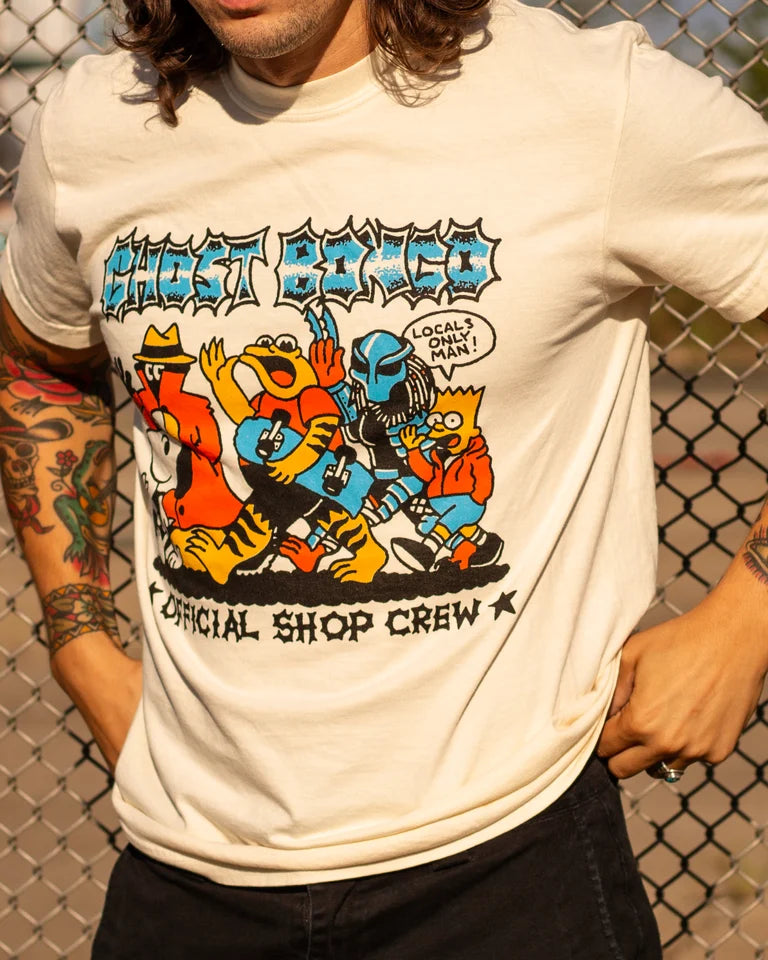 Person wearing a white t-shirt with colorful graphic design in front of a chain-link fence.